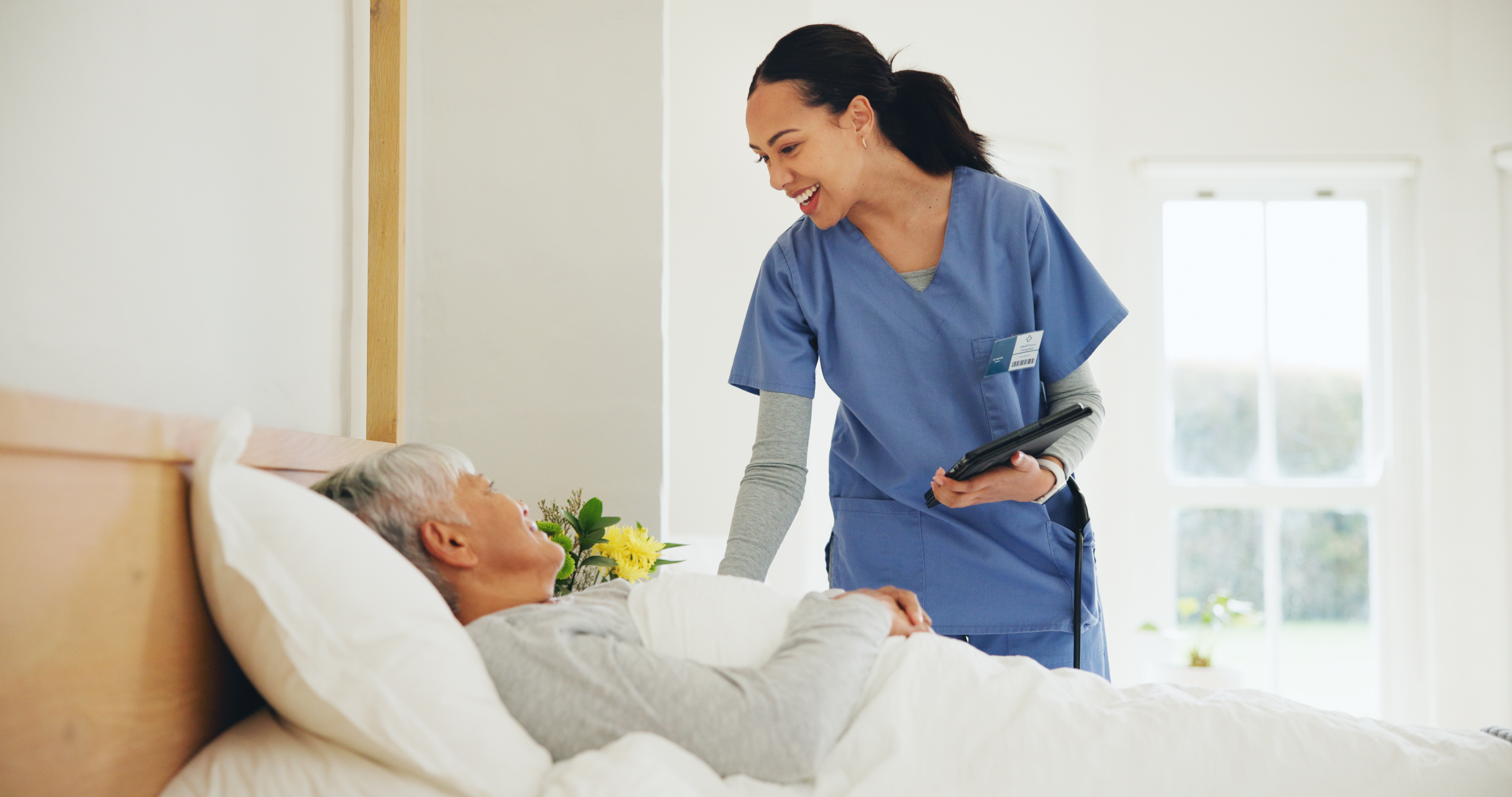 Happy woman, nurse and tablet with patient in bed, elderly care or checkup at old age home. Female person, doctor or medical caregiver smile with technology and client lying in bedroom for healthcare