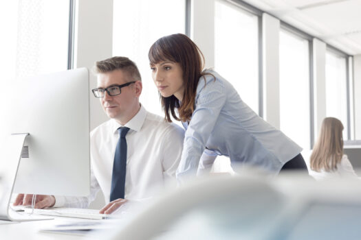 Focused businessman and businesswoman working at computer in office