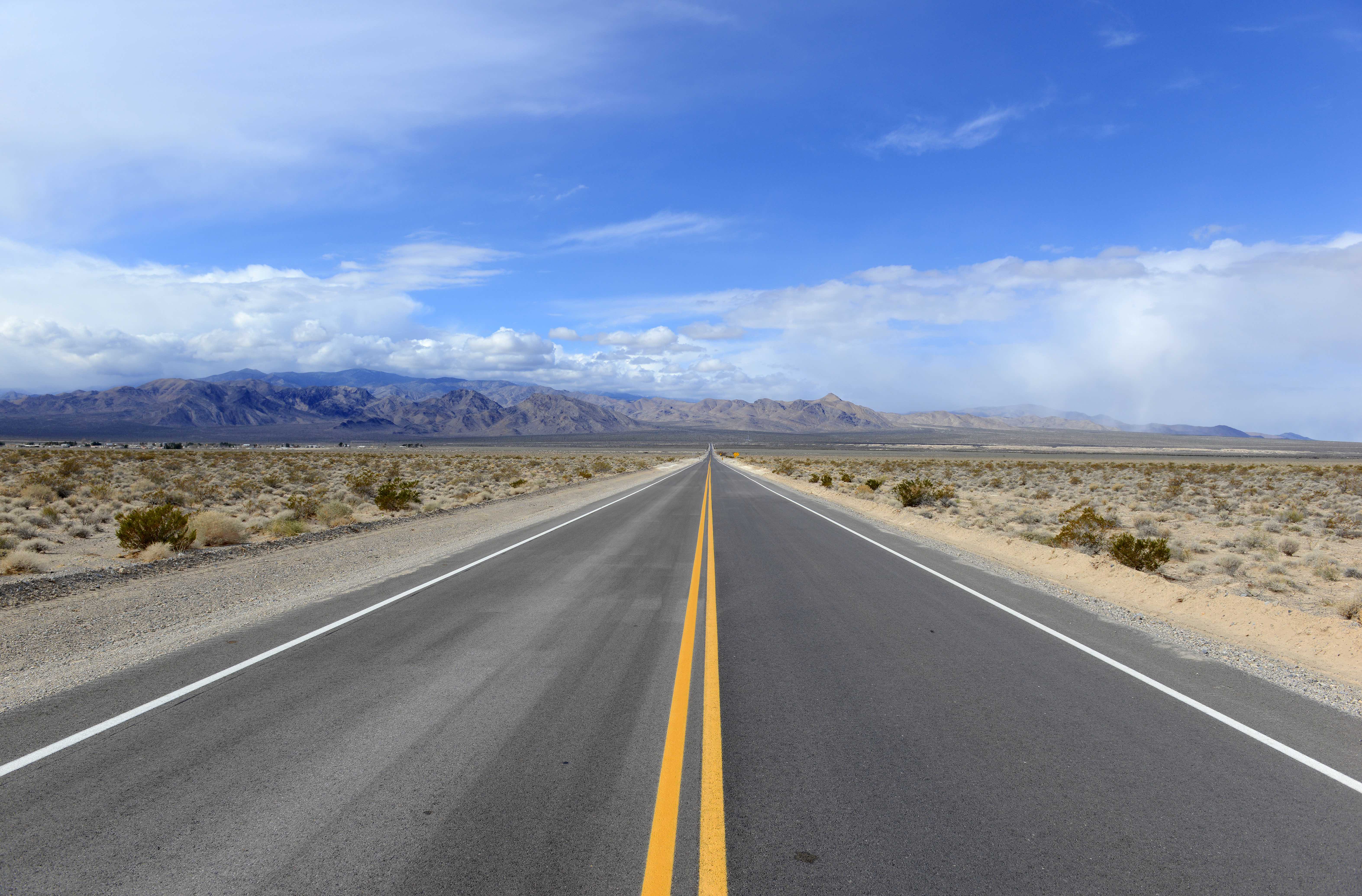 Driving on the open road in the desert with mountain backdrop